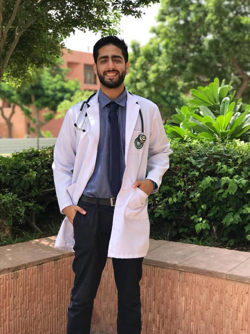 Photo of smiling Dr Haris stood outdoors in scrubs